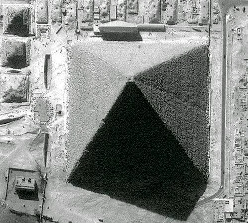 Aerial photograph of the Great Pyramid of Giza in low sunlight, showing a crease down the middle of each face